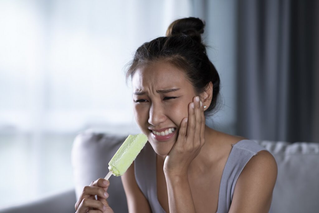 Young Asian woman have sensitive teeth with ice